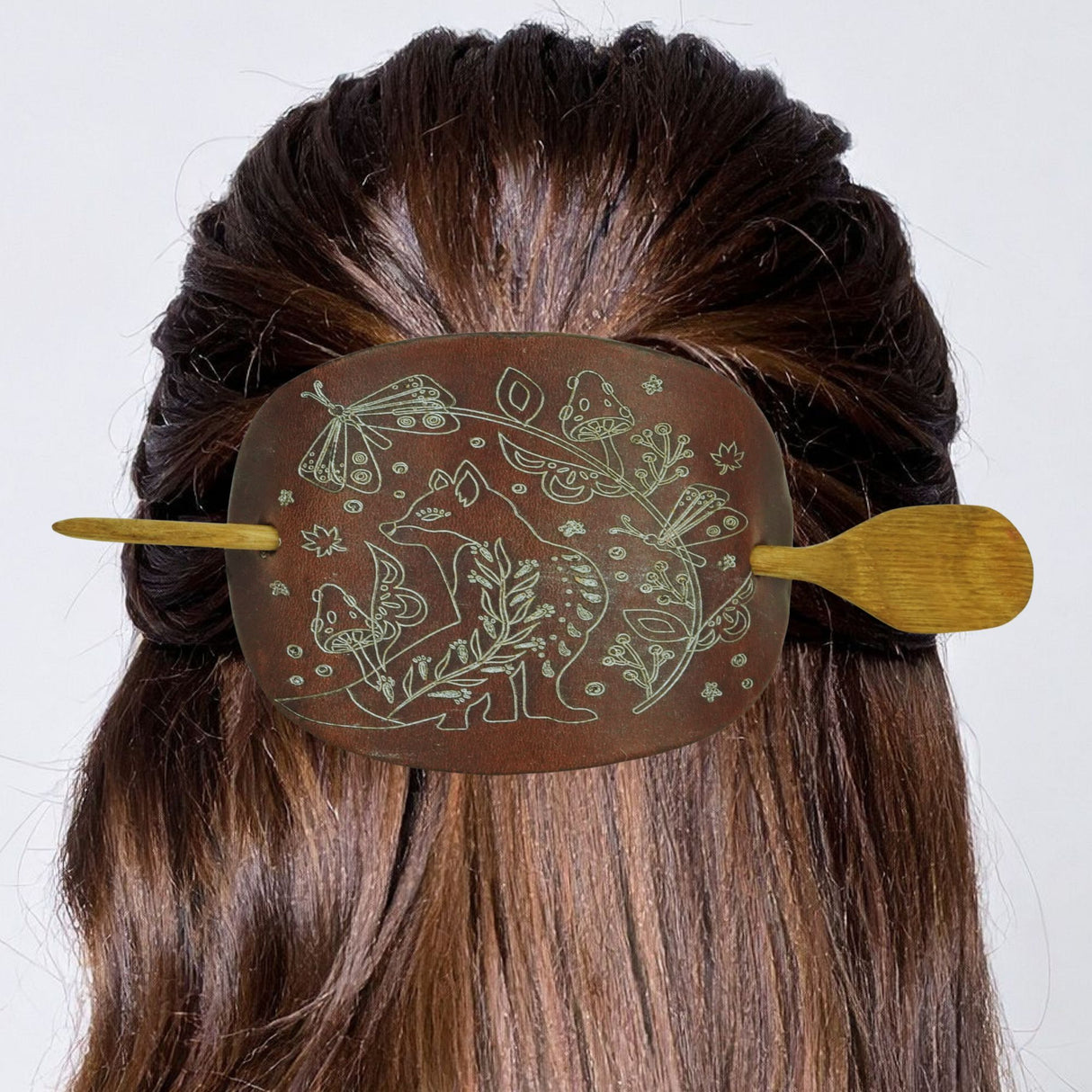 Decorative hair clip with animal designs on a person's hair against a white background
