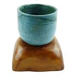 Blue ceramic cup on a wooden stand against a white background