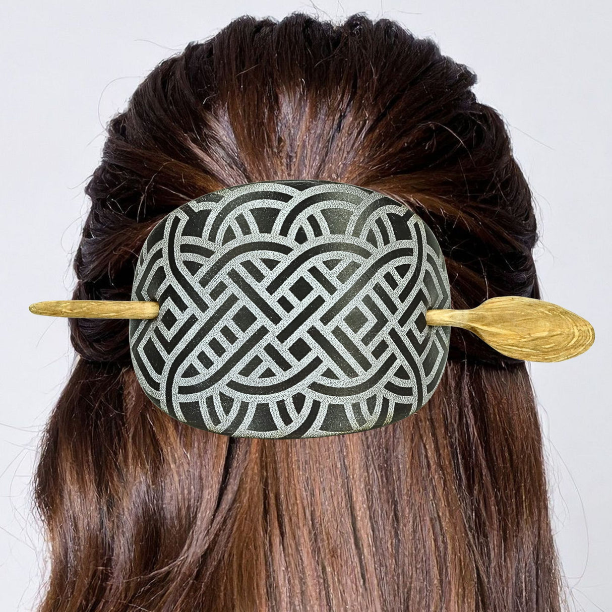 Decorative hairpin with intricate design in a person's hair against a white background