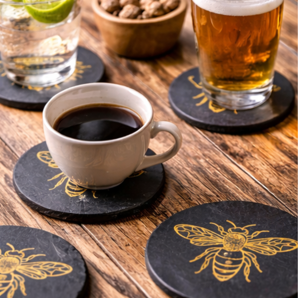 A coffee cup and drinking glass on engraved slate bee coasters.
