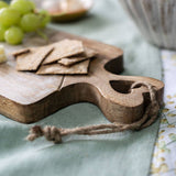 Wooden cheese board with crackers and grapes on a table