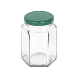 Clear hexagonal glass jar with a green lid on a white background