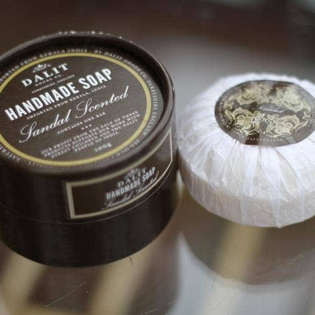 Handmade soap candle scented  with a black container labeled 'Dalit' on a reflective surface.