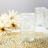 Decorative glass with floral pattern on a woven mat with flowers in the background