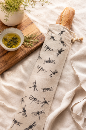 Natural linen baguette bag with black Dragonfly print, cotton drawstring, wooden toggle and hanging loop, hand printed and made in Derbyshire for storing French sticks and baguettes.