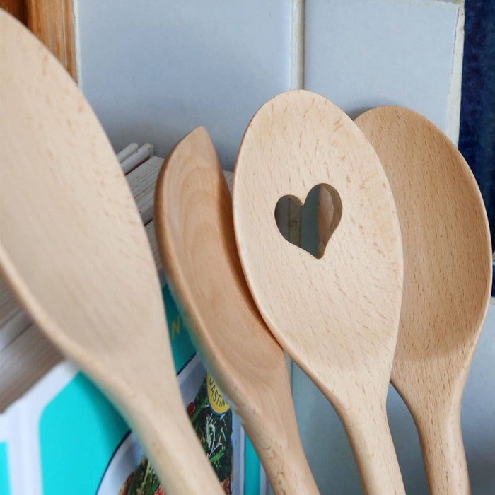 Set of wooden spoons with a heart-shaped cutout on a kitchen counter.