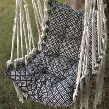 Person sitting in a black and white patterned hammock chair outdoors.