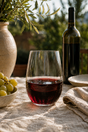 475ml stemless wine glass with red wine on a table with a bottle and grapes in the background