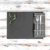 Slate platter with herbs and cutlery on a wooden surface