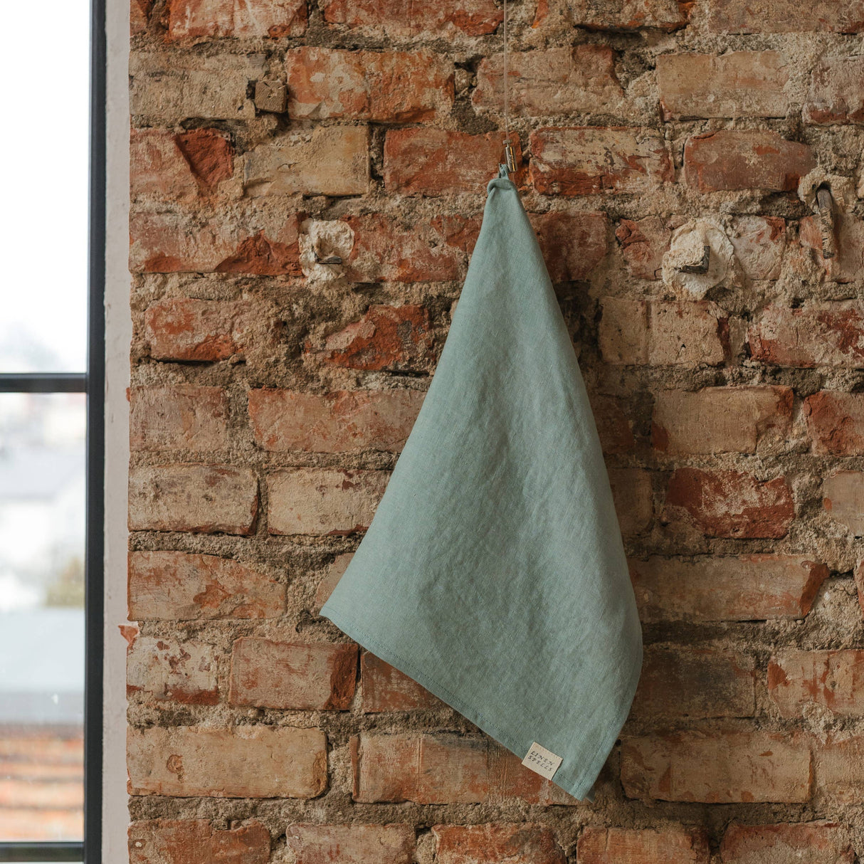 Green towel hanging on a brick wall