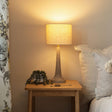 Napoleon tabelamp on a wooden side table next to a sofa with cushions.