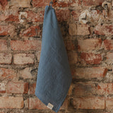 dark grey towel hanging on a brick wall