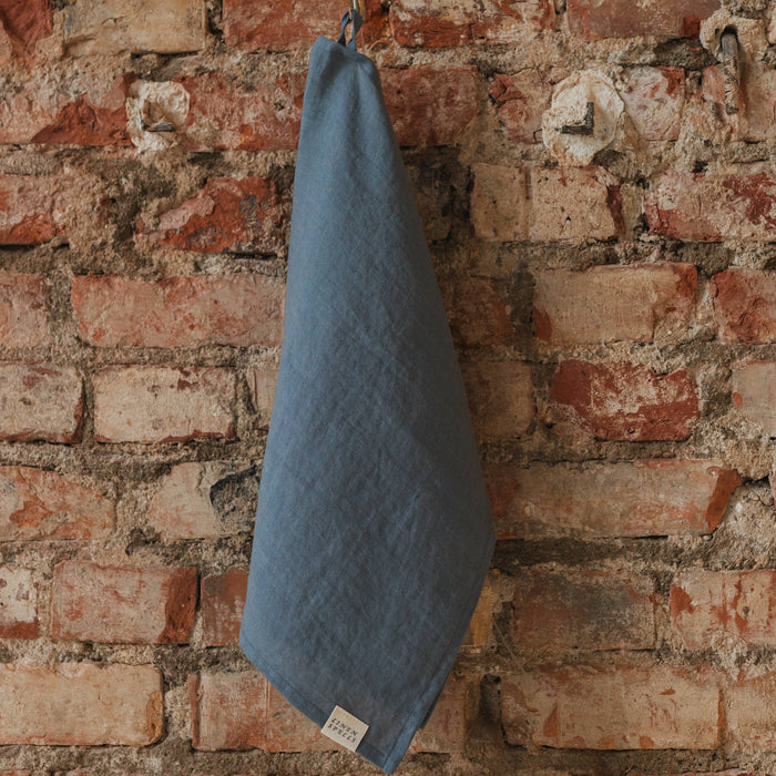 dark grey towel hanging on a brick wall
