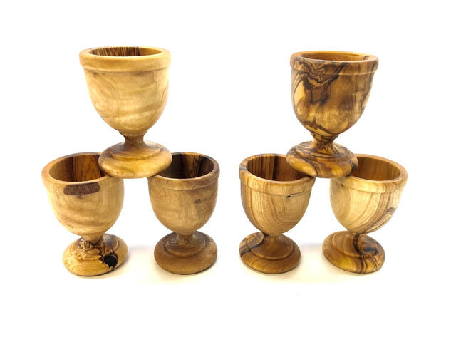 Set of six wooden egg cups stacked on a white background