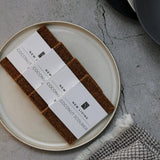 Coconut scrubber set on a plate with business cards on a textured surface