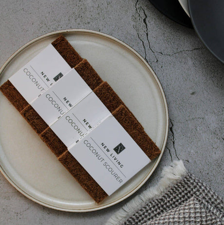 Coconut scrubber set on a plate with business cards on a textured surface