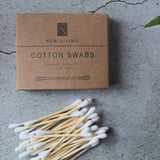 Box of New Living Cotton Swabs on a concrete surface with a plant in the background