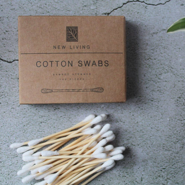 Box of New Living Cotton Swabs on a concrete surface with a plant in the background