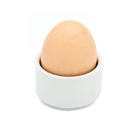 Brown egg in a white ceramic cup on a white background