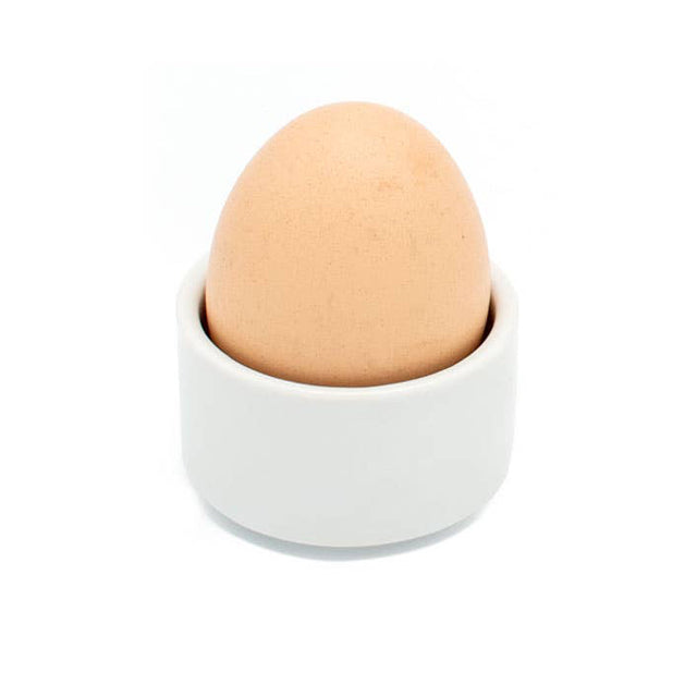 Brown egg in a white ceramic cup on a white background