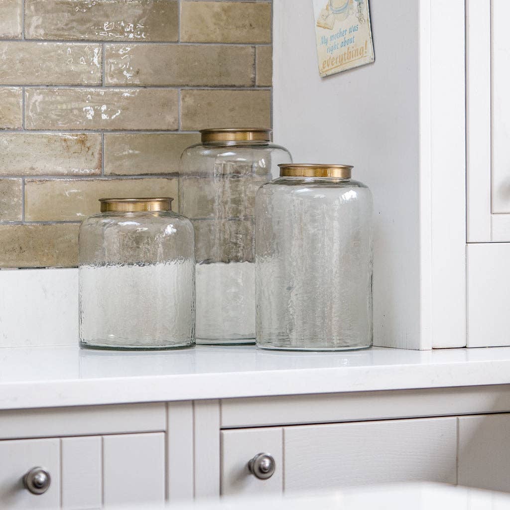Hammered glass storage jars with metal lids arranged on a kitchen counter.