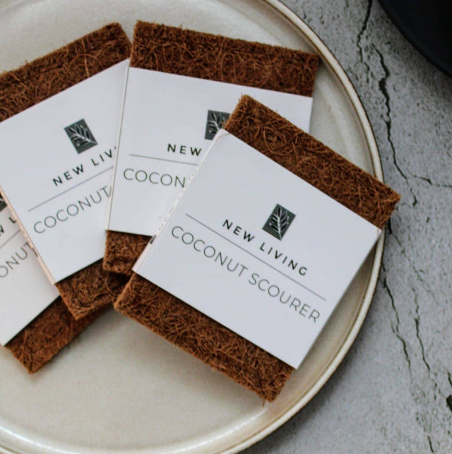 Coconut scourers on a plate with 'New Living' branding on a gray surface.