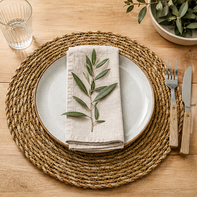 Round woven placemat on a wooden surface with a table setting.