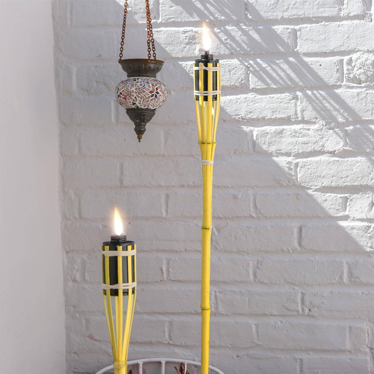 Two yellow torches with flames against a white brick wall.