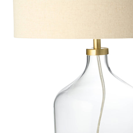 Clear glass lamp with beige lampshade on a white background