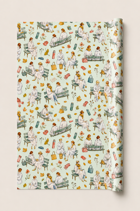A roll of wrapping paper featuring a vintage-style watercolor pattern of women in white sitting on park benches with flowers, leaves, and medical-themed items, shown against a light beige background.