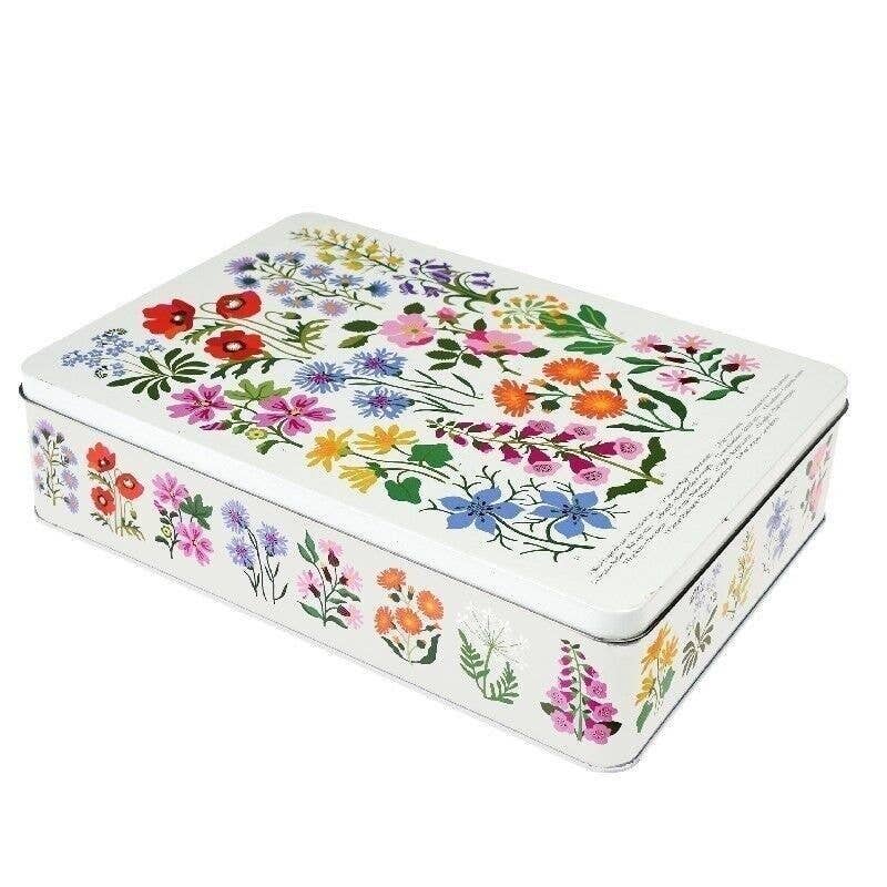 A rectangular metal tin with a white background decorated with a colorful wildflower pattern on the lid and sides, shown on a plain white background.