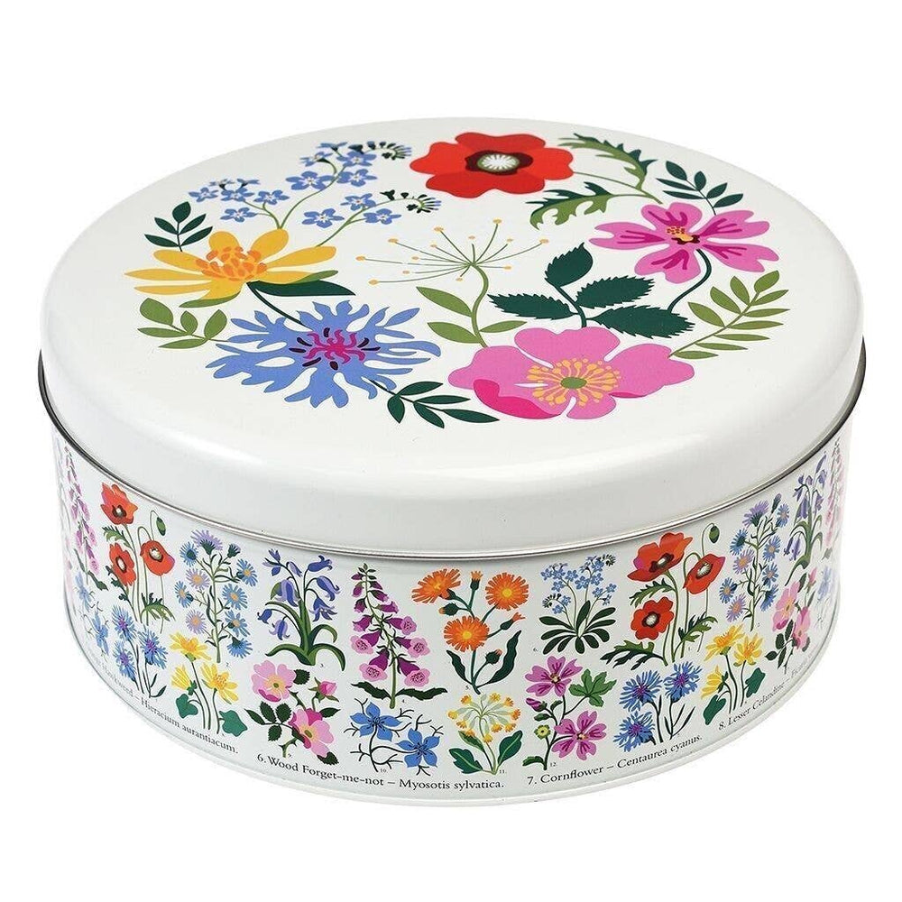 A round metal tin with a white lid and body, decorated with colorful wildflower illustrations including pink, blue, yellow, red, and purple flowers with green leaves.
