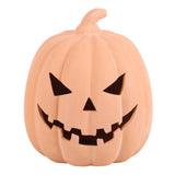 A terracotta carved jack-o'-lantern pumpkin decoration with a stitched, plastic-like texture in a warm peach-orange color, featuring black triangular eyes and a wide, jagged grin, isolated on a white background.
