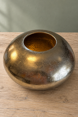 Raised view of the gold pebble bowl showing its small circular opening, gold-toned interior and mottled metal surface