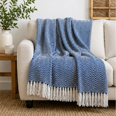 Blue herringbone blanket with white fringe layer over a sofa