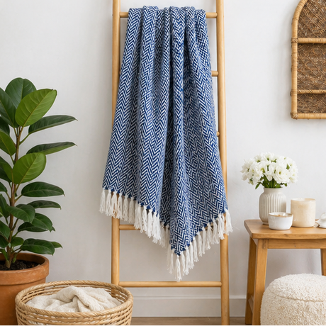 Blue herringbone blanket with white fringe displayed over a ladder