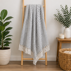 a grey and white patterned throw blanket over a ladder 