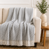 A grey and white patterned throw blanket on a sofa.
