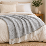 Grey and white patterned throw blanket on a bed.