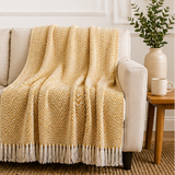 Yellow blanket with white fringe displayed over a sofa.