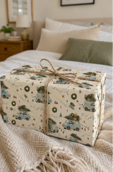 Badger Christmas wrapping paper pattern with scarf-wearing badgers driving pale-blue vintage cars loaded with fir trees, wreaths and colourful baubles.