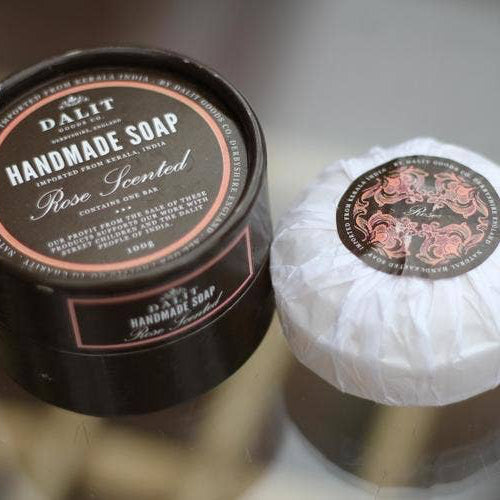 Handmade soap with a black container labeled 'DAL·IT Handmade Soap Rose Scented' on a reflective surface.