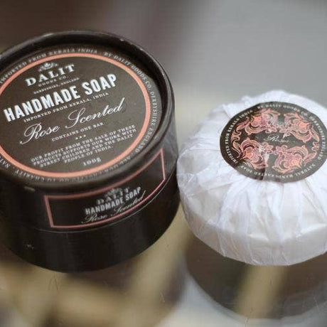 Handmade soap with a black container labeled 'DAL·IT Handmade Soap Rose Scented' on a reflective surface.