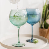 Two colorful gin glasses on a white surface with a blurred background