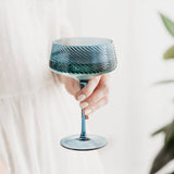 Hand holding a blue glass with a white background