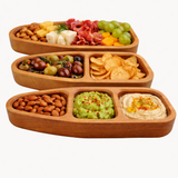 Wooden snack platter with compartments filled with various snacks on a white background