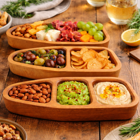Wooden snack platter with various finger foods on a wooden table.