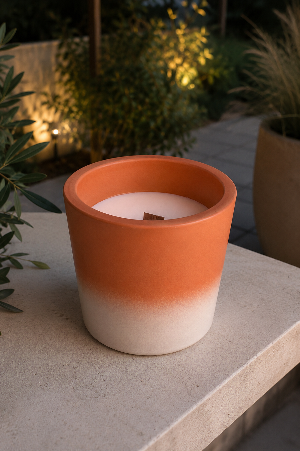 terracotta candle holder with gradient design on a stone surface with plants in the background