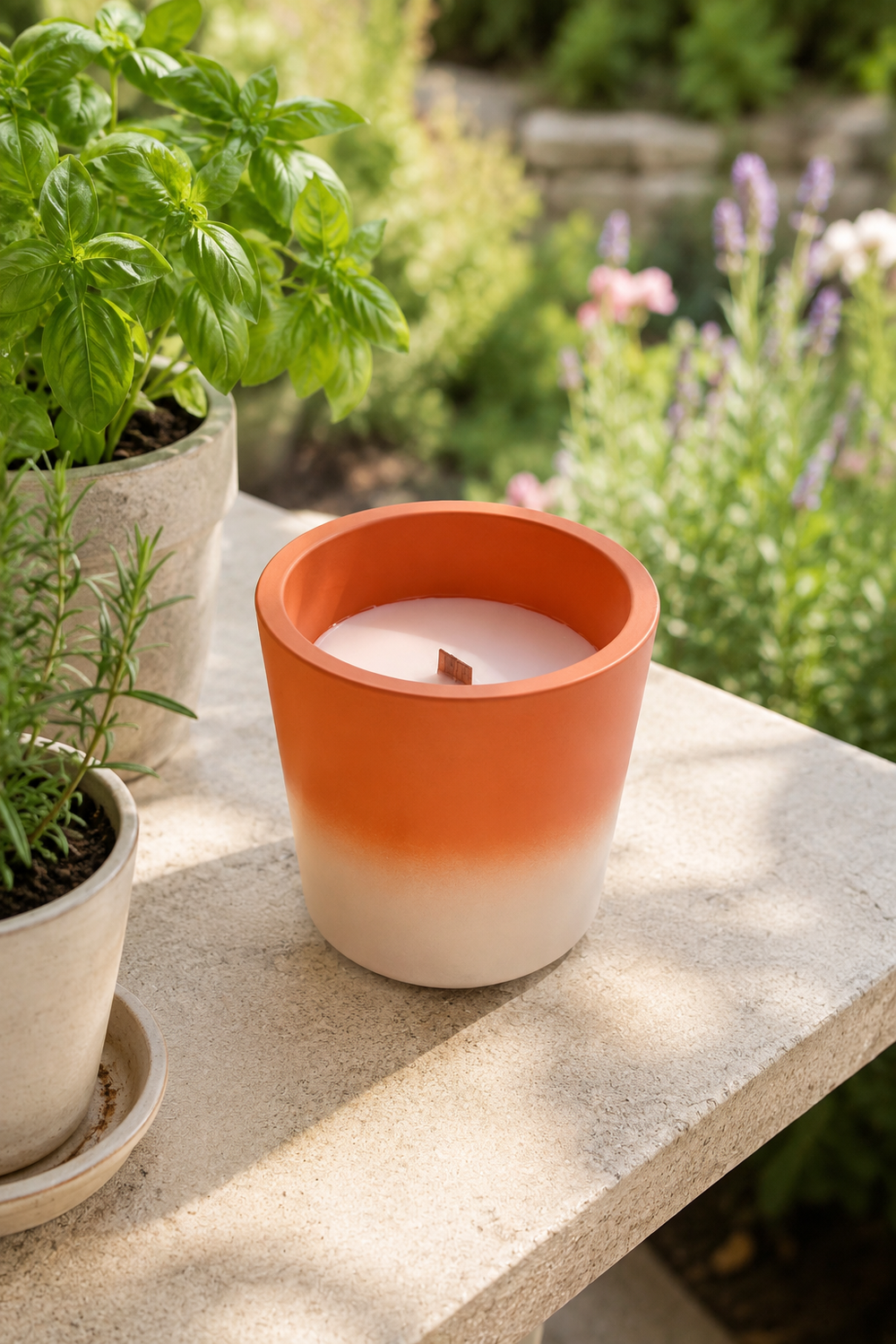 candle in a terracotta orange and white pot on a stone surface with plants in the background