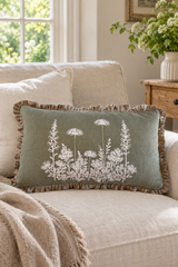 Rectangular sage Florilegium linen cushion with white botanical print and natural ruffle on an oatmeal sofa.